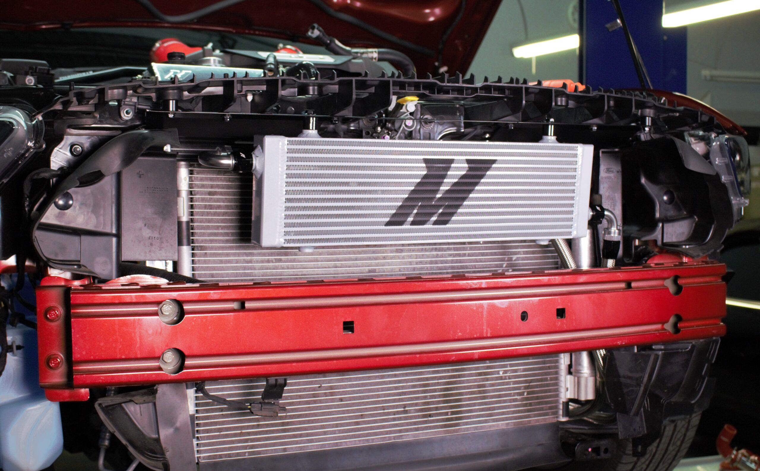Application-specific mounting bracket and air diversion shield for the Mishimoto Mustang GT oil cooler